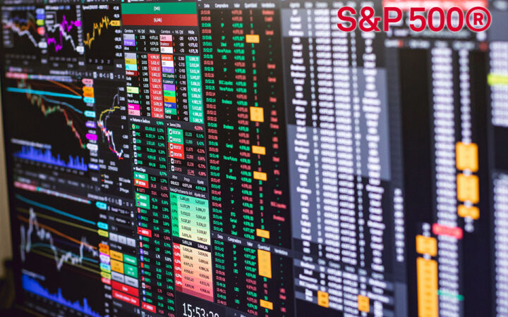 Multiple monitor screens showing colorful stock charts and market data with a prominent S&P 500® logo in red at the top right.